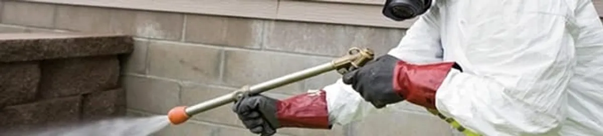 Pest control technician applying exterior insect treatment along a home foundation in El Paso, TX